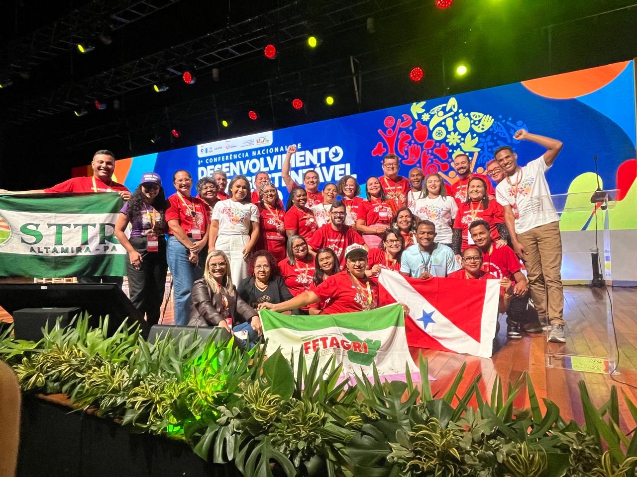 Imagem mostra grupo de pessoas com camisas e exibindo bandeira do Pará em palco de evento