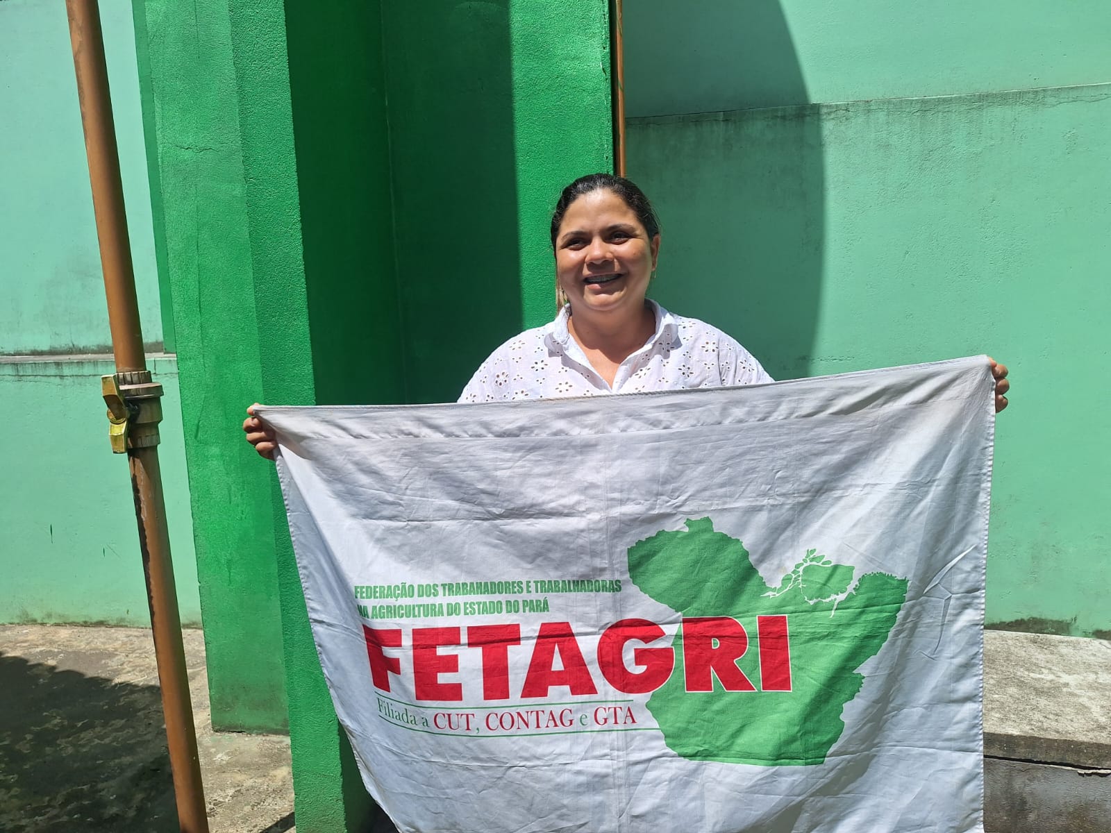 Foto mostra mulher com bandeira da Fetagri 
