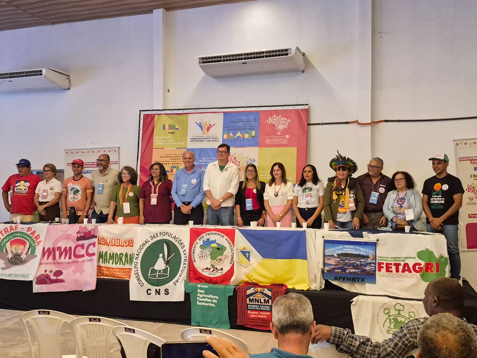 Imagem mostra 15 pessoas de pé na composição da mesa da conferência