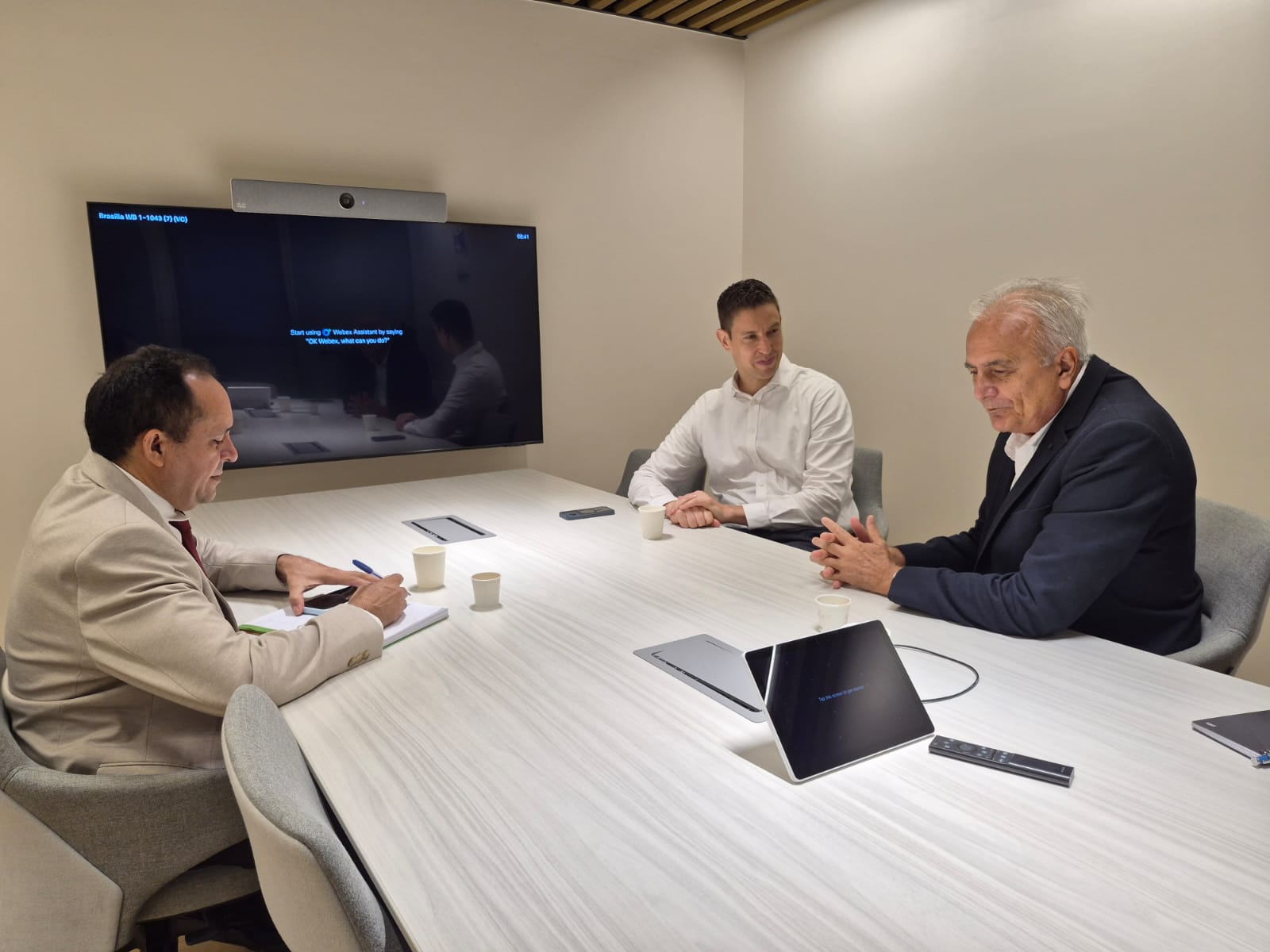 Imagem mostra reunião entre três homens em uma mesa